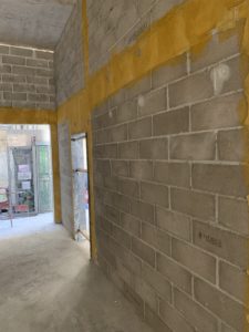 Voile en parpaings pleins , chaînages horizontaux et verticaux coulés en place, application d'un produit d'accrochage avant enduit