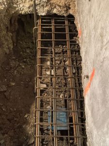 BATI-IDF cage d'armatures d'une longrine en béton armé en sous-œuvre, vue d'ensemble longitudinale au pied du mur de fondation existant — reprise en sous-œuvre post-sécheresse à Antony (92).