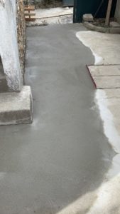 BATI-IDF dalle béton fraîchement coulée et lissée au pied du mur en meulière, finition propre des travaux de reprise en sous-œuvre post-sécheresse à Antony (92).