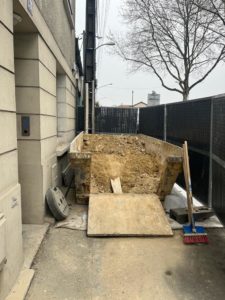 BATI-IDF benne à déblais sur la zone de stockage clôturée le long de l'immeuble — chantier de reprise en sous-œuvre, Argenteuil (95)