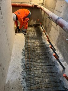 BATI-IDF mise en place du ferraillage du radier en béton armé en fond de fouille, entre les voiles de reprise déjà coulés — reprise en sous-œuvre, Argenteuil (95)