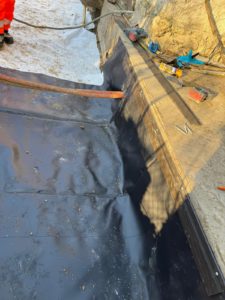 BATI-IDF géomembrane PVC ép. 1 mm en place au sol et chevillée en pied de façade par la bande porte-solin métallique — étanchéité périphérique anti-sécheresse — Boissy-sans-Avoir (78).
