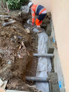 BATI-IDF tranchée en pied de façade préparée pour la reconstitution du réseau de drainage, géotextile et regards en place — reprise en sous-œuvre d'une maison à Bruley (54).