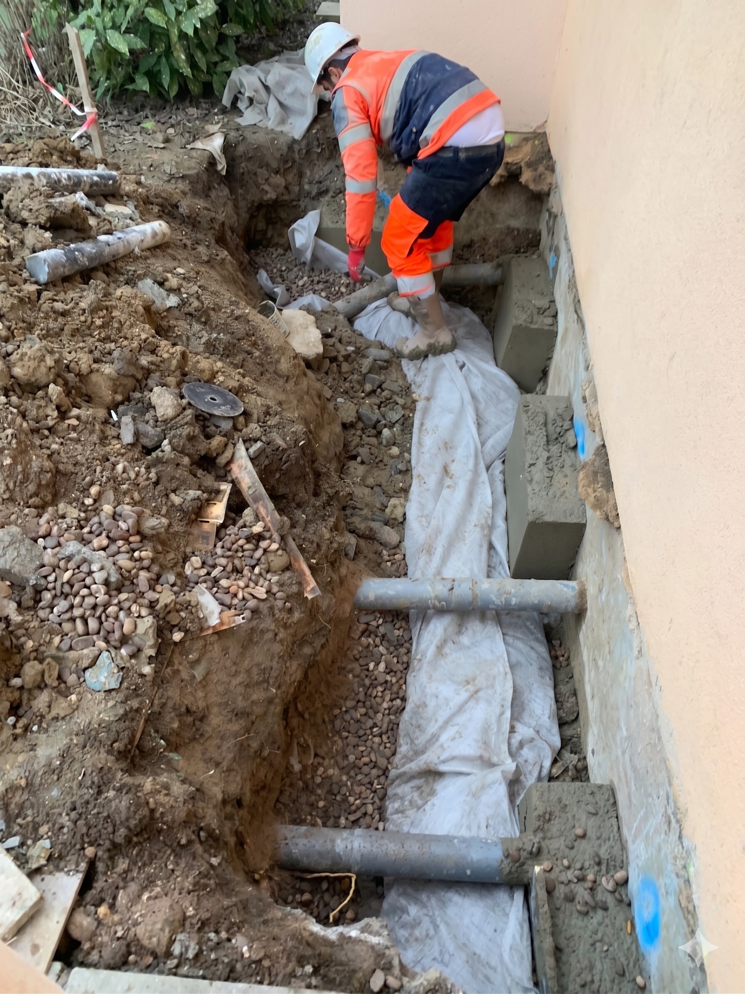 BATI-IDF tranchée en pied de façade préparée pour la reconstitution du réseau de drainage, géotextile et regards en place — reprise en sous-œuvre d'une maison à Bruley (54).