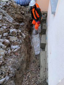 BATI-IDF compagnon dans la tranchée d'approche du massif de liaisonnement, en pied de façade — reprise en sous-œuvre d'une maison à Bruley (54).