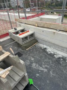 BATI-IDF mise en place d'un élément préfabriqué de caniveau technique sur ses plots de calage en mortier, réglage altimétrique au niveau — CDG Express, Saint-Denis (93)