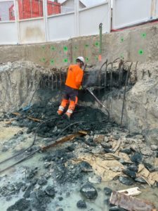BATI-IDF compagnon en pleine démolition au petit marteau-piqueur de la tête d'un panneau de paroi moulée, jusqu'au retour du béton sain. Puits OA 605, Ligne 16-3 du Grand Paris Express, Chelles.