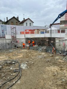 BATI-IDF équipe coulant le béton frais à la toupie mixo pompe dans le coffrage de la nouvelle arase de paroi moulée. Puits OA 605, Ligne 16-3 du Grand Paris Express, Chelles.