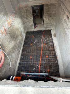 BATI-IDF radier de l'extension de sous-sol entièrement ferraillé sur polyane d'étanchéité, rehausseurs orange maintenant le treillis à la cote, prêt pour le coulage — Herblay-sur-Seine (95).