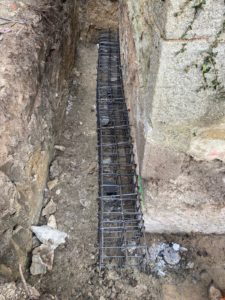 BATI-IDF cage d'armatures de longrine en contre-œuvre dans la fouille le long du mur de l'église de Noailly — reprise en sous-œuvre