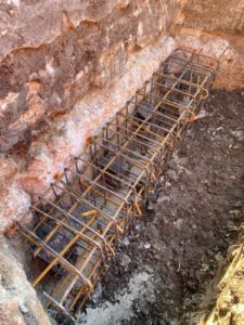 BATI-IDF longrine ferraillée posée sur le béton de propreté en fond de fouille — reprise en sous-œuvre de l'église de Noailly, Loire