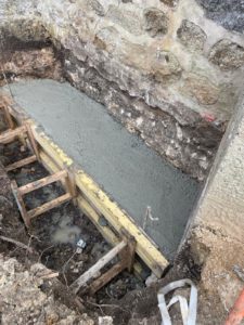 BATI-IDF coulage de la longrine en béton armé contre le mur en moellon de l'église de Noailly — reprise en sous-œuvre, Loire