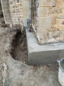 BATI-IDF longrine en béton armé décoffrée au pied du mur en moellon de l'église de Noailly — reprise en sous-œuvre