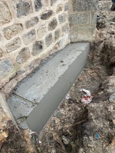 BATI-IDF longrine en béton armé achevée contre le mur en moellon de l'église de Noailly — nouvelle assise stable, reprise en sous-œuvre