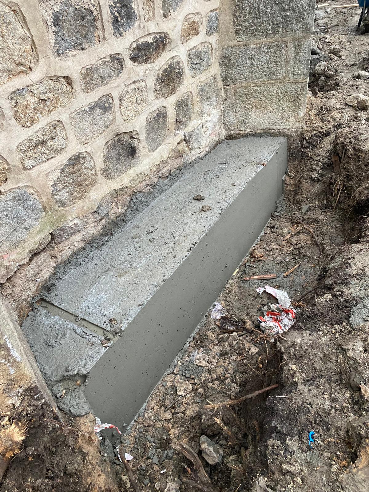 BATI-IDF longrine en béton armé achevée contre le mur en moellon de l'église de Noailly — nouvelle assise stable, reprise en sous-œuvre