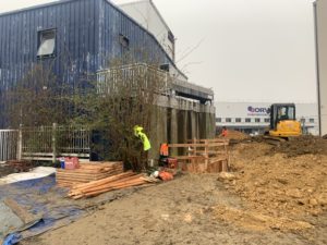 BATI-IDF vue d'ensemble du chantier de reprise en sous-œuvre à Orly (94) : mur existant, mini-pelle Yanmar, stockage du bois de coffrage et compagnon au travail.