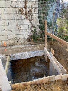 BATI-IDF passe de reprise en sous-œuvre ouverte sous un mur en parpaings, cage ferraillée en place et coffrage bois latéral — chantier RSO à Orly (94).