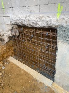BATI-IDF cage d'armatures double rangée en place sous un mur en parpaings, avec passe adjacente déjà bétonnée à droite — RSO par passes alternées à Orly (94).