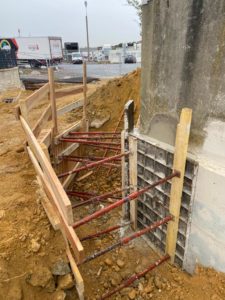 BATI-IDF coffrage bois et étais en place le long du mur en pied de site industriel, prêt pour la coulée de la nouvelle passe — RSO Orly (94).