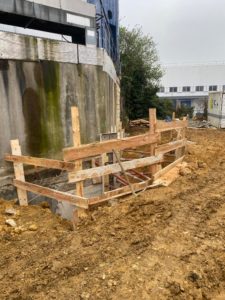 BATI-IDF coffrage bois et étais en place en pied du mur béton existant du site industriel d'Orly (94), prêt pour le bétonnage de la semelle de reprise.