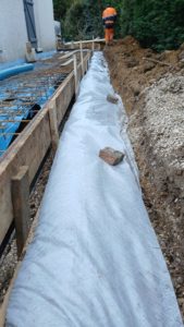 BATI-IDF vue d'ensemble du dispositif complet : drain bleu sous géotextile à droite, trottoir périphérique ferraillé à gauche en attente du bétonnage — Ouges (21).