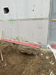 BATI-IDF pied de mur existant montrant un affouillement / cavité en partie basse, justifiant la reconnaissance précise des fondations avant nouveau projet — Saint-Lô (50).
